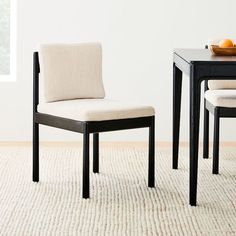 a dining room table with two chairs and a bowl of oranges on the table