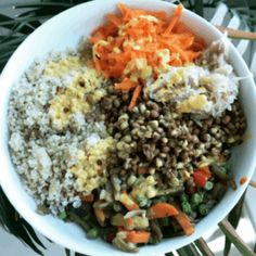 a white bowl filled with rice, carrots and lentils on top of a table