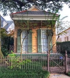 an old house with green shutters and iron fence