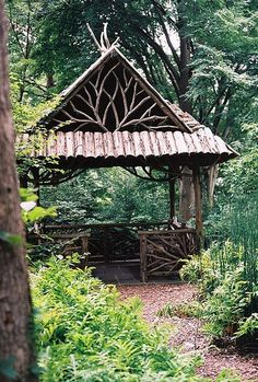 a wooden gazebo in the middle of a forest