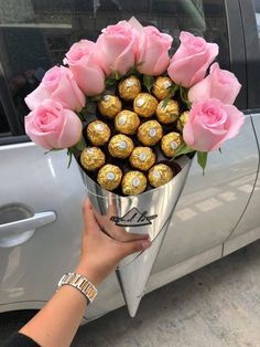 a bouquet of pink roses and chocolates in front of a silver car with a sticker on it