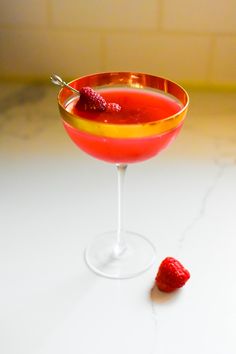 a glass filled with liquid and topped with a strawberry