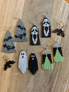 the beaded ghost earrings are hanging from hooks on a wooden table with other beads