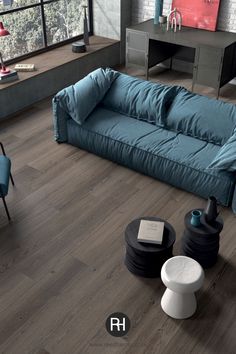 a blue couch sitting on top of a hard wood floor next to a chair and table