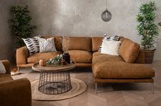 a living room filled with lots of furniture and pillows on top of wooden flooring