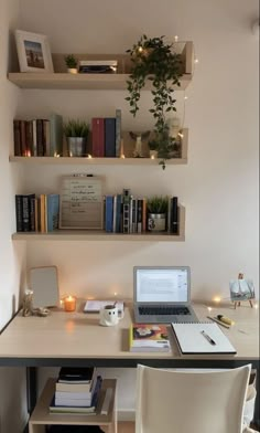 a laptop computer sitting on top of a desk next to a book shelf filled with books