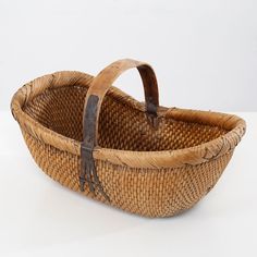 a woven basket with leather handles on a white surface