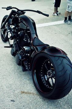 a black motorcycle parked on top of a parking lot next to other people in the background