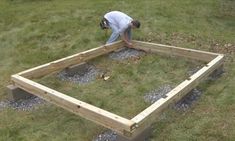 a man working on building a raised garden bed in the yard with gravel and grass