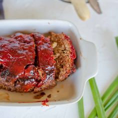 meatloaf with ketchup and green onions in a white dish