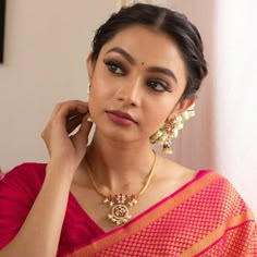 a woman in a red sari is posing for the camera with her hand on her ear