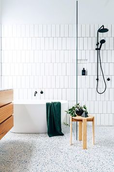 a bath tub sitting next to a wooden table in front of a white tiled wall