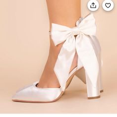 a woman's white high heeled shoes with a bow on the side