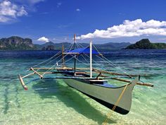 a boat floating on top of a body of water next to an island in the ocean