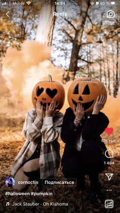 two people wearing pumpkin heads sitting in the woods