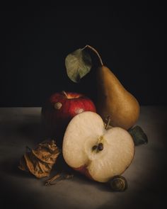 apples, pears and leaves on a table with a dark backround background