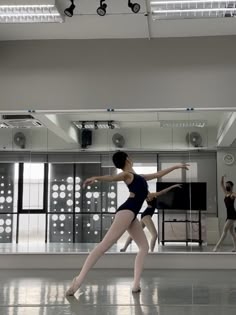 two ballerinas in black leotards and white tights are dancing on the dance floor