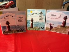 three cards with lighthouses on them are sitting on a red tablecloth covered table