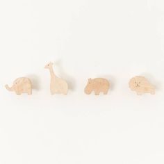 four wooden animals are lined up in a row on a white surface with one giraffe, the other an elephant