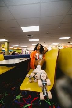 a woman sitting on top of a yellow bench with a skateboard in front of her