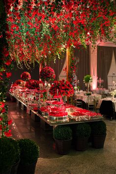 a long table covered in red flowers and greenery