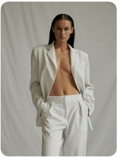 a woman in white pinstripe suit posing for the camera with her shirt open