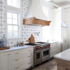 a kitchen with an oven, stove and counter top in the center is decorated with geometric wallpaper