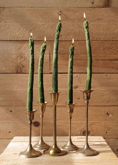 three brass candlesticks with green beans in them