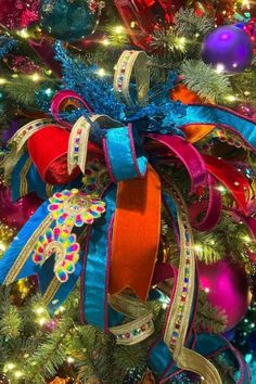 a christmas tree decorated with colorful ribbons and ornaments in the shape of an ornament