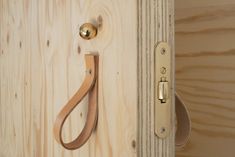 a close up of a door handle on a wooden wall with a leather strap hanging from it