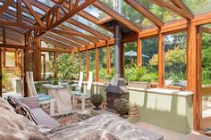 a covered patio with chairs, tables and an open fire place in the center surrounded by greenery