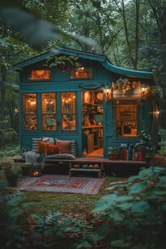 a small blue cabin in the woods with lots of lights on it's windows