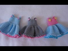 three crocheted dresses are lined up on a white blanket