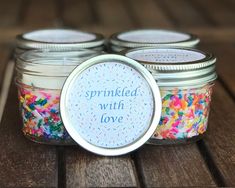 three jars filled with sprinkled with love on top of a wooden table next to each other