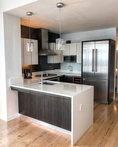 an empty kitchen with stainless steel appliances and wood flooring is pictured in this image