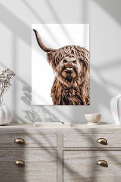 an animal with long hair standing in front of a white wall and some flowers on the dresser