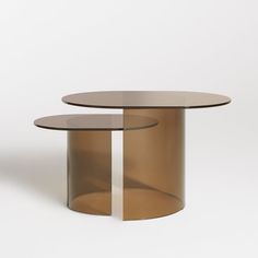 two round tables sitting next to each other on a white surface, one with a glass top