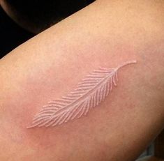 a close up of a person's arm with a white leaf tattoo on it