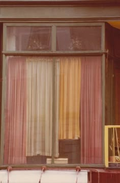 an open window with curtains and a suitcase