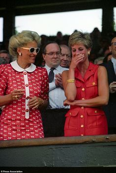 two women in red and white dress standing next to each other at a sporting event