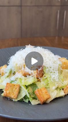 a salad on a plate with parmesan cheese and croutons in the middle