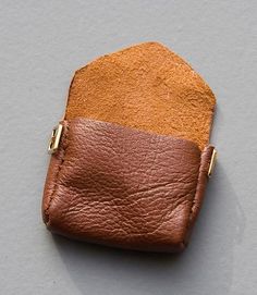 a brown and tan leather pouch sitting on top of a white table next to a gray wall