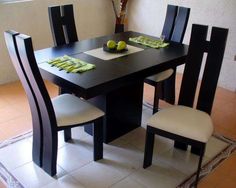 a dining table with four chairs and two green apples on the plate in front of it