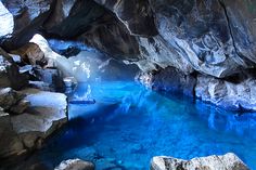 a blue pool in the middle of a rocky area with water flowing from it's sides