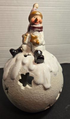 a small snowman sitting on top of a rock