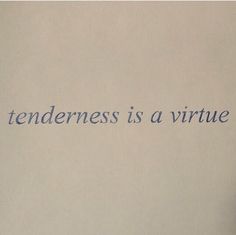 a hand holding a cell phone in front of a wall with the words tenderness is a virtue written on it