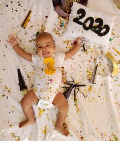 a baby is laying down with confetti all around him