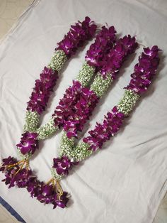 three purple and white flowers are arranged on a sheet