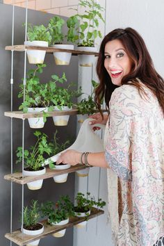 a woman standing in front of a shelf filled with plants