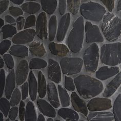 a stone wall that is made out of black and brown rocks, with some white dots in the middle